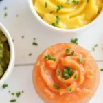 A variety of colorful homemade baby purees, including avocado, carrot, and lentil blends, garnished with fresh herbs for maximum nutrition.